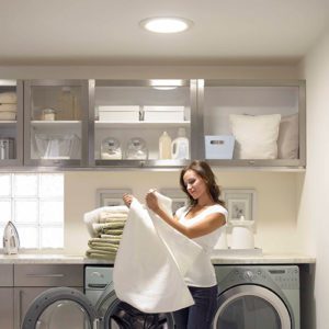 product-inset_suntunnel A woman folding laundry with a sun tunnel above her.