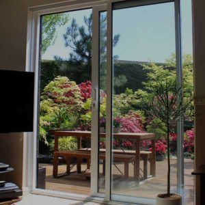 products_slidingdoorsreduced A glass door with screen, outlooking onto a garden and patio.