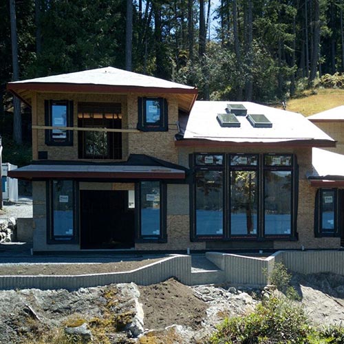 A new home being constructed with lots of various windows and dark trim for the windows.